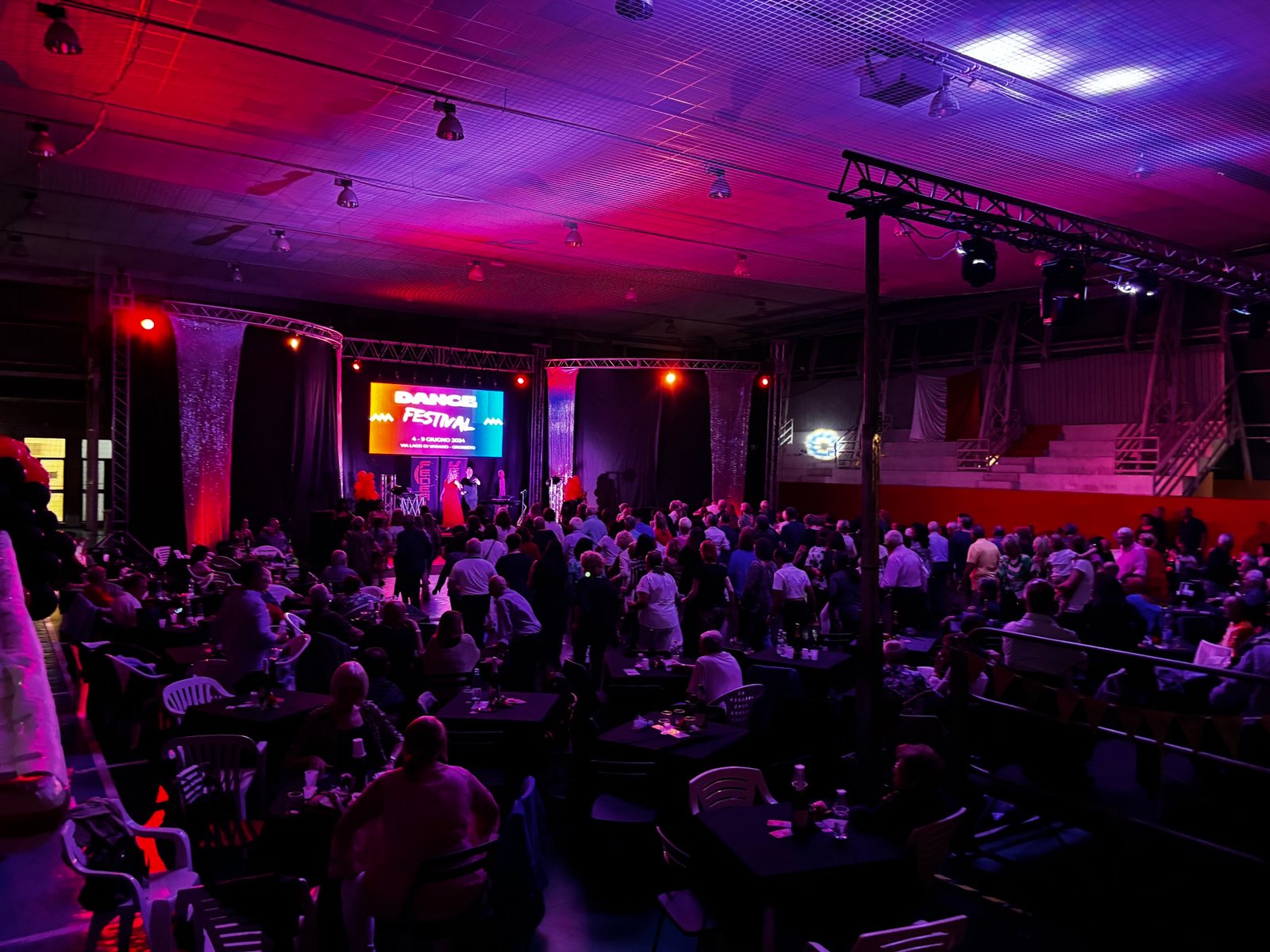 Pubblico e palco del Dance Festival con illuminazione rossa e viola